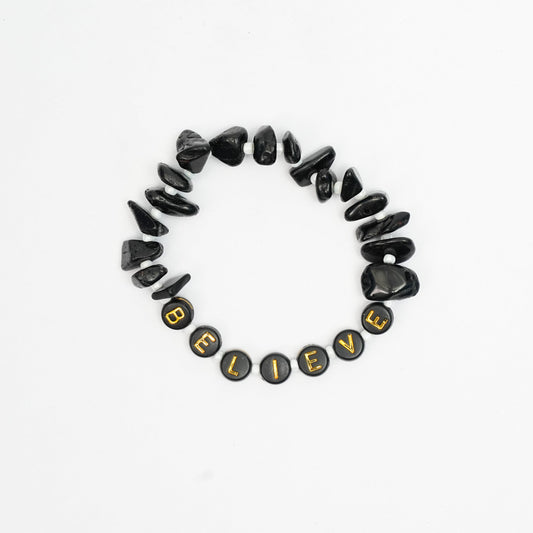 Black stone bracelet with 'BELIEVE' beads on a white background